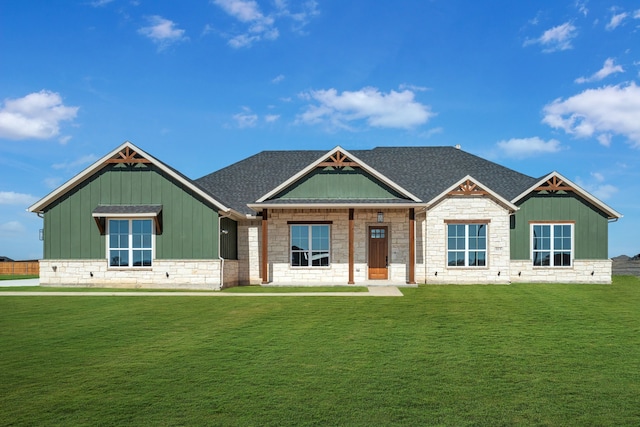 craftsman-style home with board and batten siding, a front yard, and a shingled roof