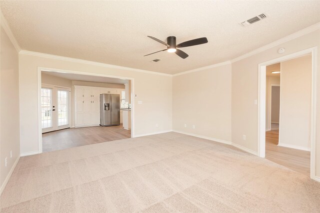 empty room featuring light carpet, ceiling fan, and a textured ceiling