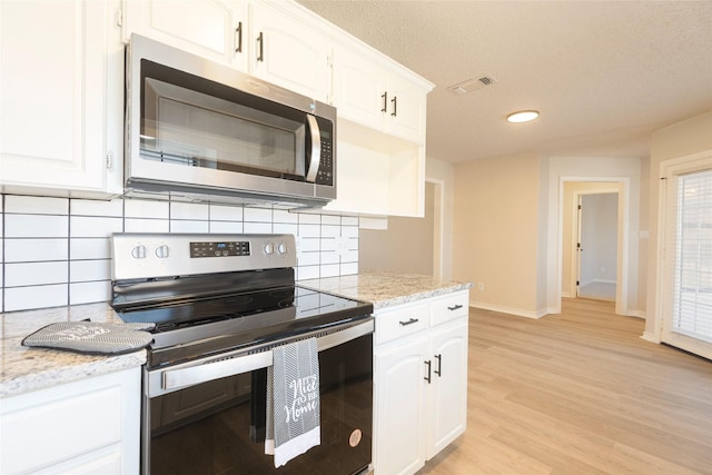 kitchen with light stone counters, white cabinets, and stainless steel appliances