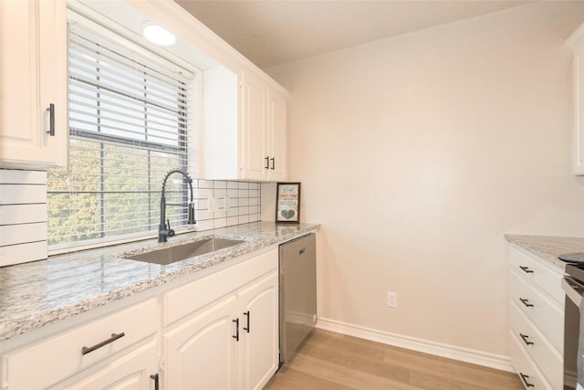 kitchen featuring light stone countertops, white cabinetry, sink, and stainless steel dishwasher