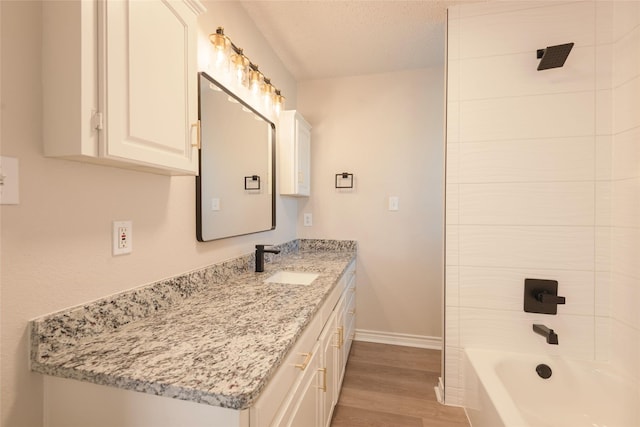 bathroom with bathtub / shower combination, wood-type flooring, vanity, and a textured ceiling