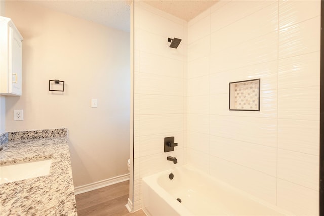 full bathroom featuring toilet, a textured ceiling, vanity, tiled shower / bath combo, and hardwood / wood-style floors