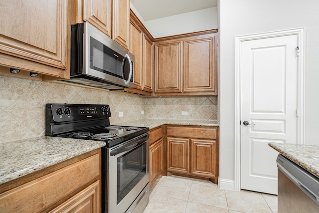 kitchen with tasteful backsplash, light stone countertops, light tile patterned floors, and stainless steel appliances