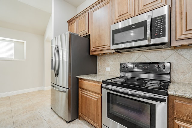 kitchen featuring light tile patterned floors, light stone countertops, and appliances with stainless steel finishes