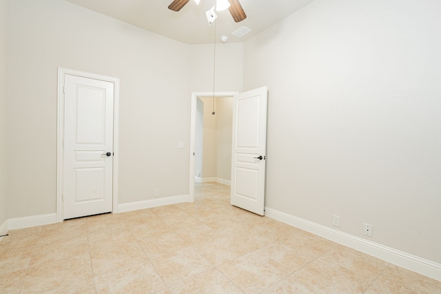 tiled spare room with ceiling fan and a towering ceiling