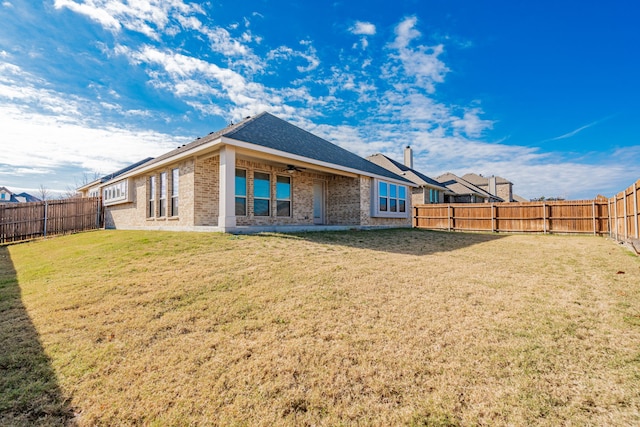 rear view of property with a lawn and ceiling fan