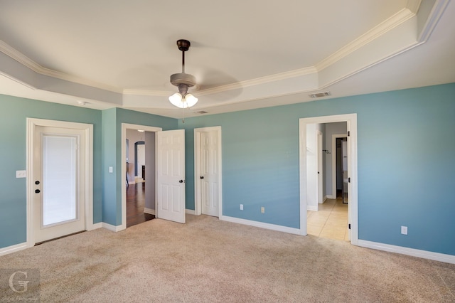 unfurnished bedroom with ceiling fan, light colored carpet, ornamental molding, and a tray ceiling