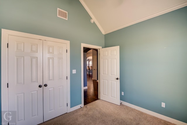 unfurnished bedroom with high vaulted ceiling, ornamental molding, carpet floors, and a closet