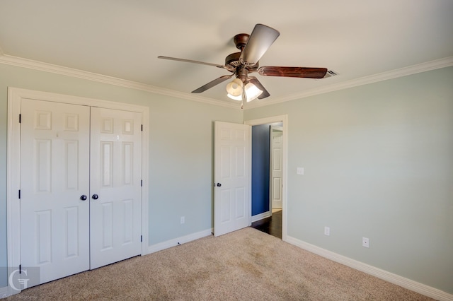 unfurnished bedroom with crown molding, carpet floors, a closet, and ceiling fan