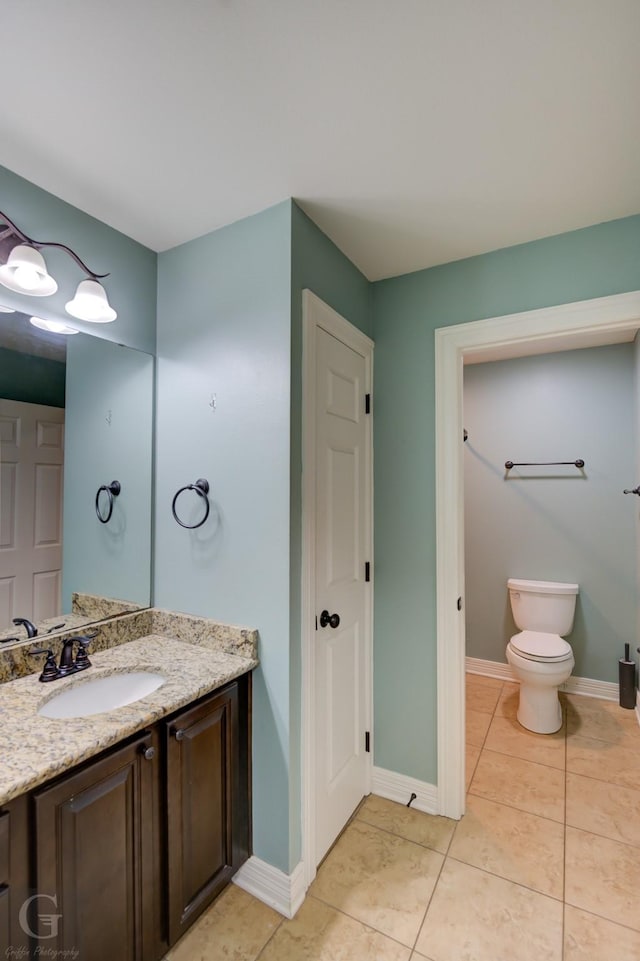 bathroom with toilet, vanity, and tile patterned floors