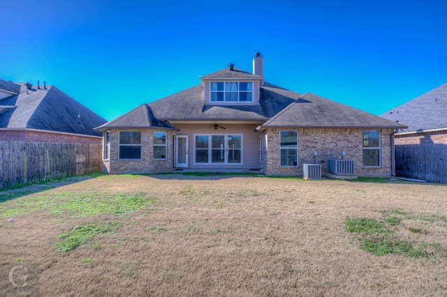 rear view of property with central AC unit, ceiling fan, and a yard