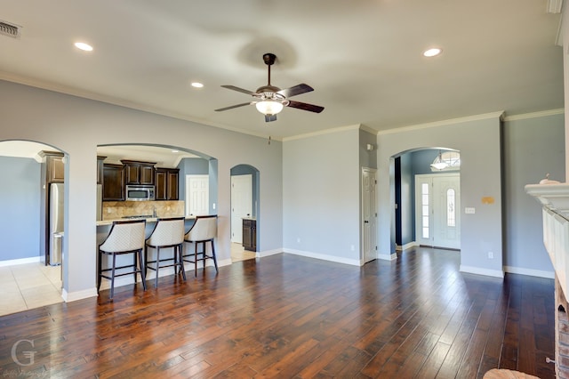 living room featuring ceiling fan, ornamental molding, and dark hardwood / wood-style flooring