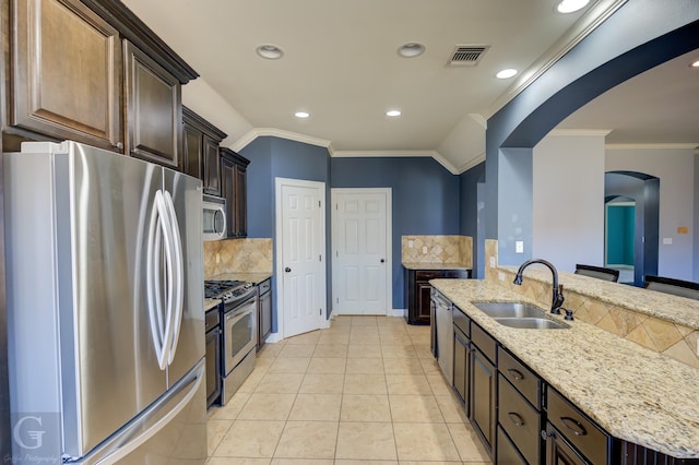 kitchen with sink, stainless steel appliances, crown molding, an island with sink, and vaulted ceiling