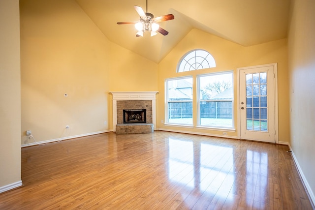 unfurnished living room featuring ceiling fan, a fireplace, high vaulted ceiling, and light wood-type flooring