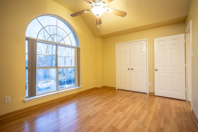 unfurnished bedroom featuring lofted ceiling, a closet, ceiling fan, and light wood-type flooring