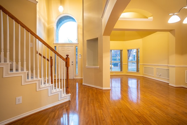 foyer featuring wood-type flooring and a towering ceiling