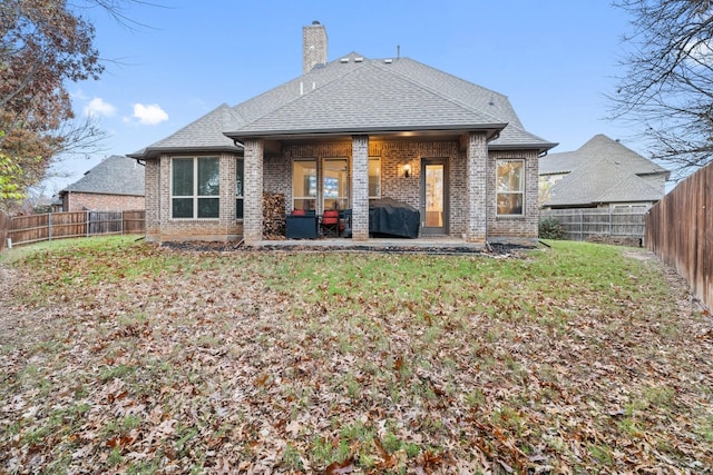 back of property with a yard and a patio