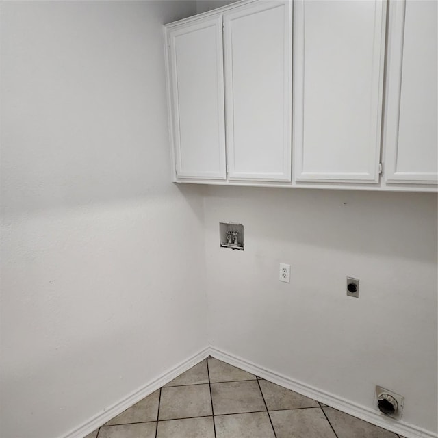 laundry area featuring electric dryer hookup, light tile patterned floors, hookup for a washing machine, and cabinets