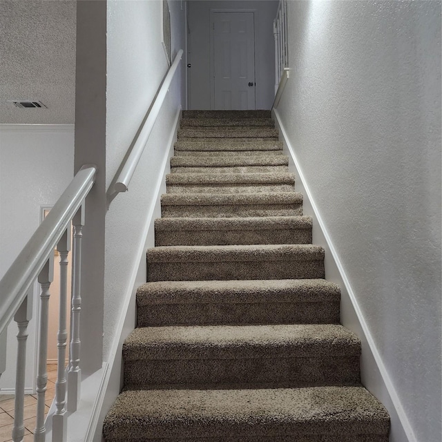 stairs with a textured ceiling