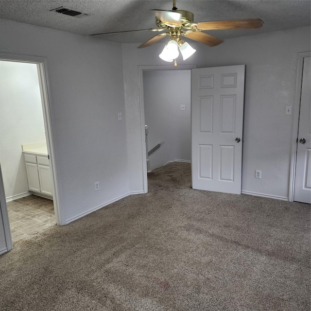 interior space with ceiling fan, light colored carpet, a textured ceiling, and ensuite bath