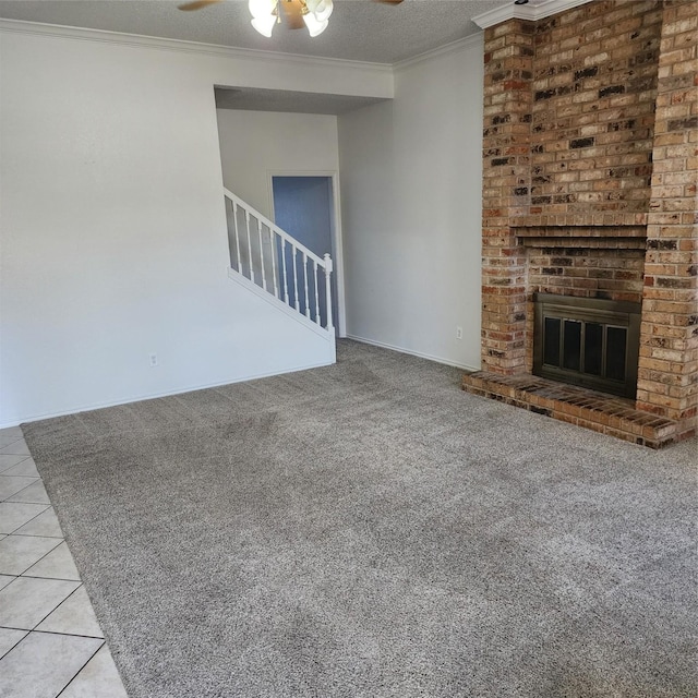 unfurnished living room with light tile patterned floors, crown molding, ceiling fan, a fireplace, and a textured ceiling