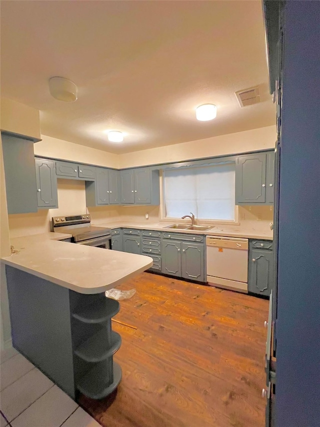 kitchen with hardwood / wood-style floors, dishwasher, stainless steel range with electric cooktop, sink, and kitchen peninsula