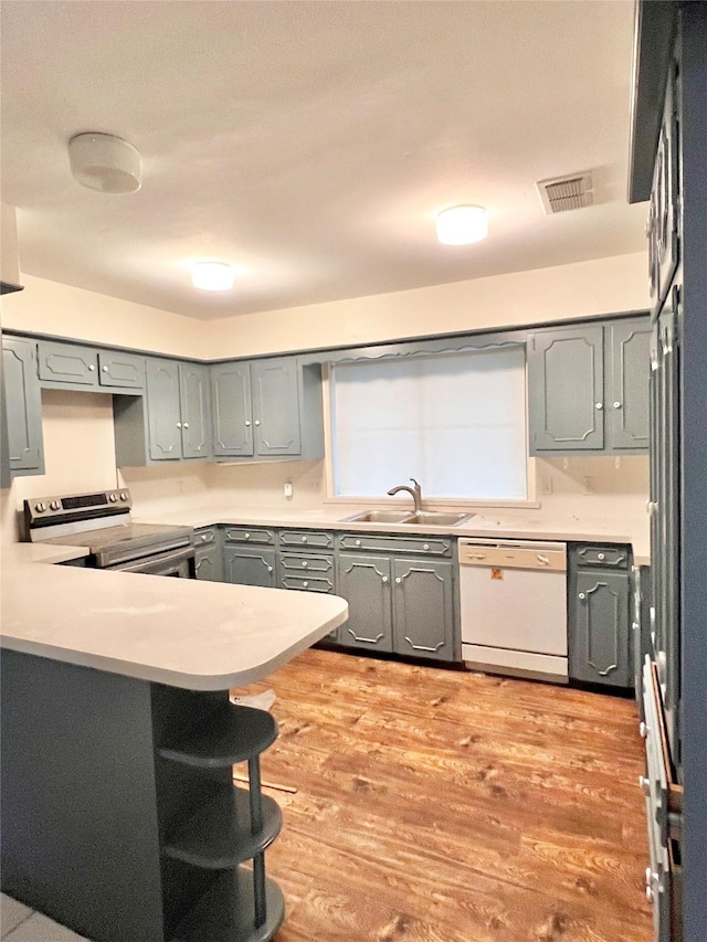 kitchen featuring sink, range with electric stovetop, kitchen peninsula, white dishwasher, and light hardwood / wood-style floors