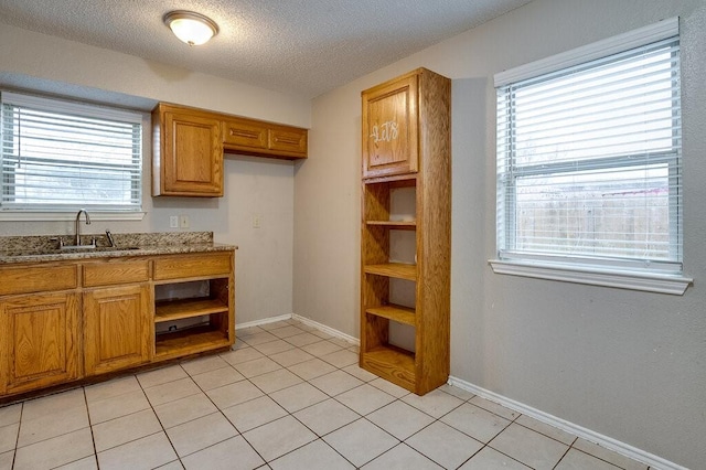 kitchen with a textured ceiling, light stone countertops, sink, and a wealth of natural light