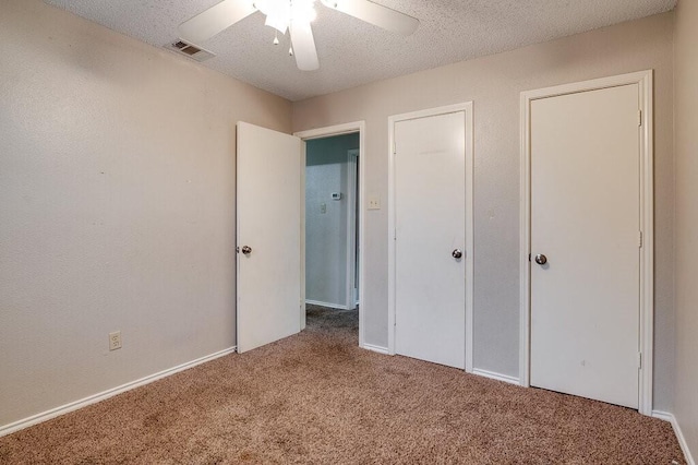 unfurnished bedroom featuring carpet, ceiling fan, and a textured ceiling