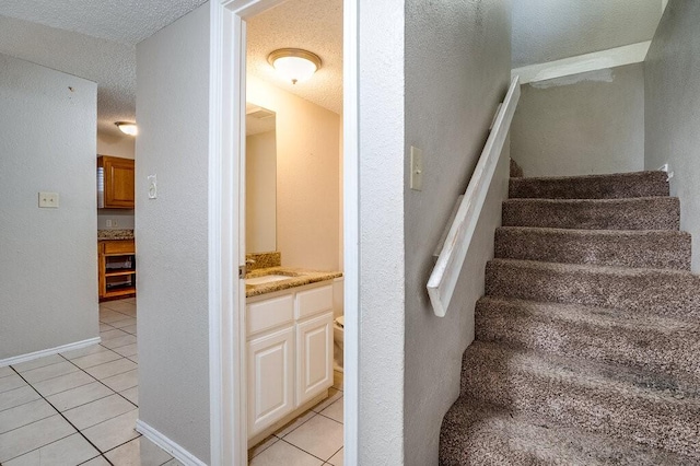 staircase featuring tile patterned floors, sink, and a textured ceiling