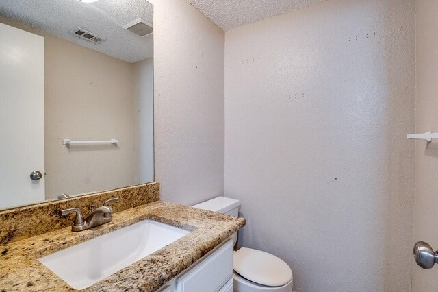 bathroom with vanity, a textured ceiling, and toilet