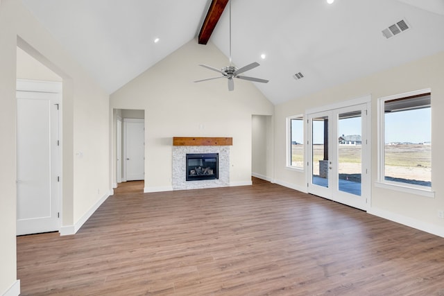 unfurnished living room featuring visible vents, wood finished floors, beamed ceiling, and a glass covered fireplace