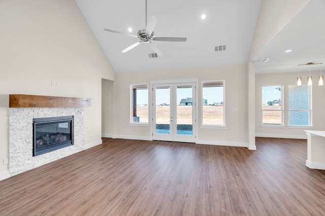 unfurnished living room featuring a glass covered fireplace, visible vents, baseboards, and wood finished floors