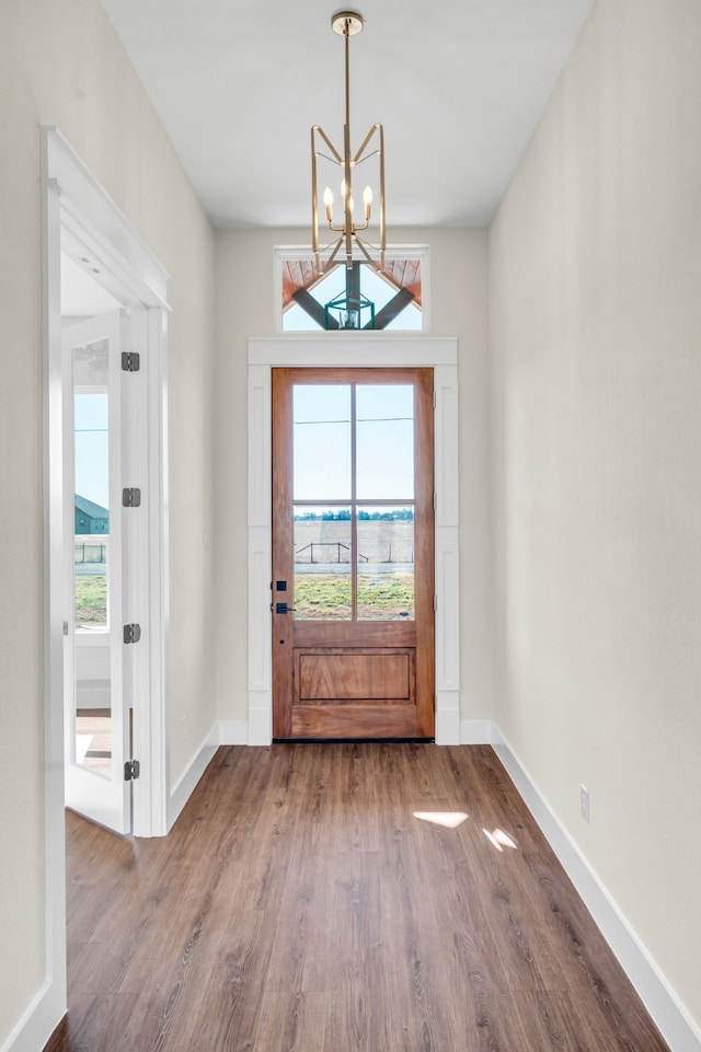 entryway with baseboards, an inviting chandelier, wood finished floors, and a healthy amount of sunlight