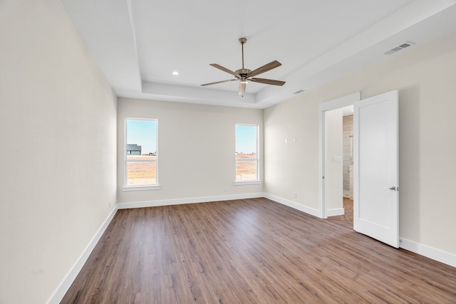 unfurnished room featuring ceiling fan, baseboards, a raised ceiling, and wood finished floors