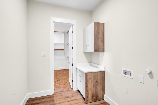 laundry room with parquet floors, cabinet space, baseboards, and washer hookup