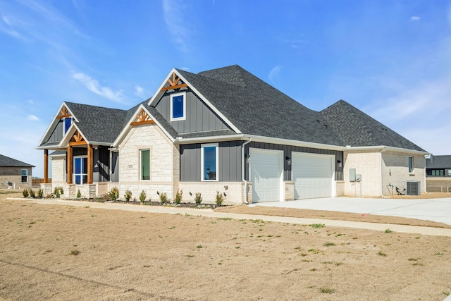 craftsman inspired home with central air condition unit, a shingled roof, an attached garage, board and batten siding, and driveway