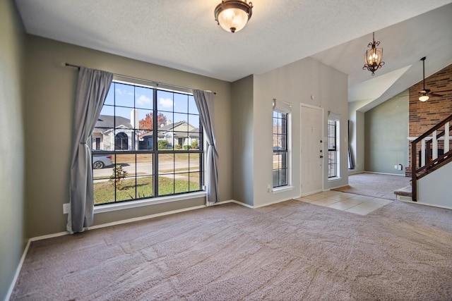 carpeted foyer with ceiling fan with notable chandelier, a textured ceiling, vaulted ceiling, and a healthy amount of sunlight