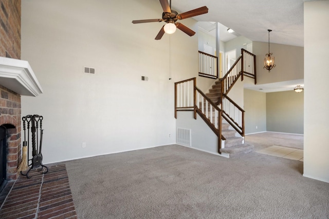 unfurnished living room featuring carpet flooring, ceiling fan with notable chandelier, high vaulted ceiling, and a brick fireplace