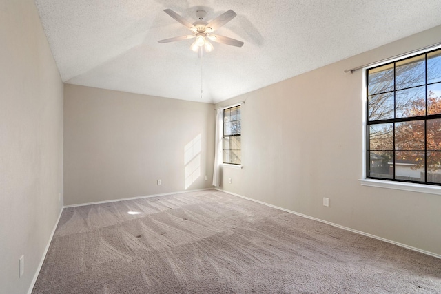 empty room featuring carpet flooring, lofted ceiling, ceiling fan, and a textured ceiling