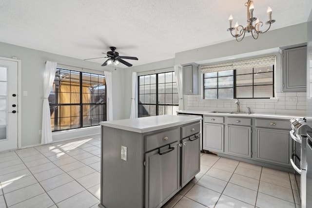 kitchen with a center island, ceiling fan with notable chandelier, sink, gray cabinets, and tasteful backsplash