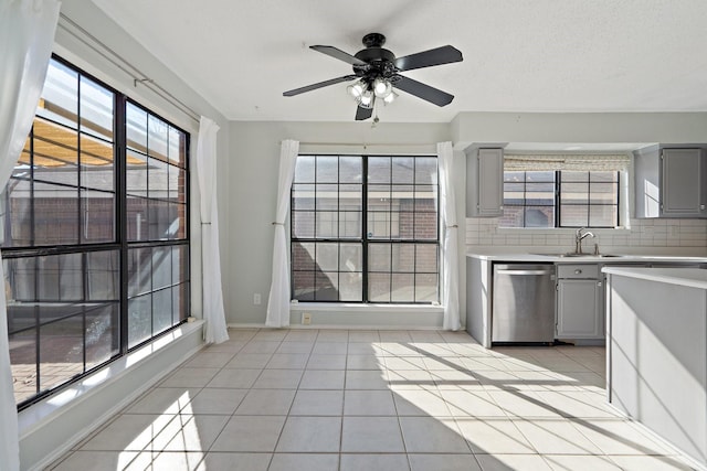 kitchen with sink, stainless steel dishwasher, ceiling fan, gray cabinets, and light tile patterned flooring