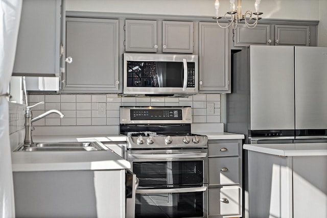 kitchen featuring gray cabinets, decorative backsplash, sink, and appliances with stainless steel finishes