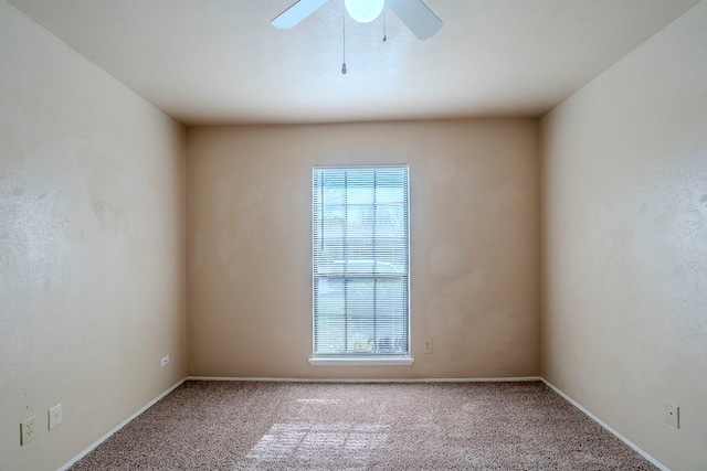 carpeted spare room featuring a wealth of natural light and ceiling fan