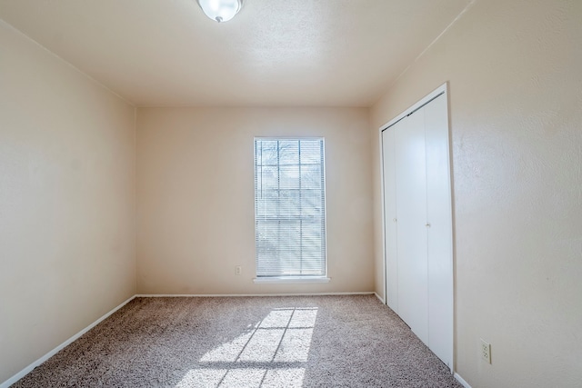 unfurnished bedroom with light colored carpet and a closet