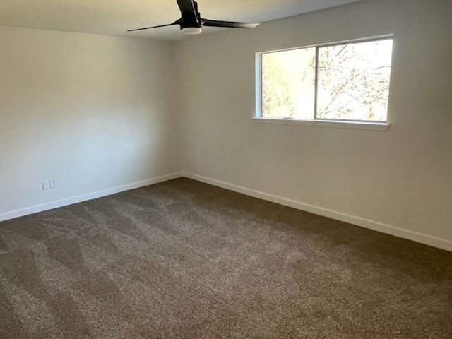 unfurnished room with ceiling fan and dark carpet