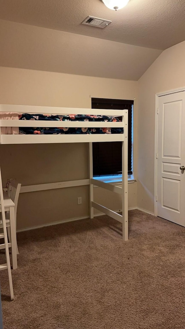 unfurnished bedroom with carpet, lofted ceiling, and a textured ceiling