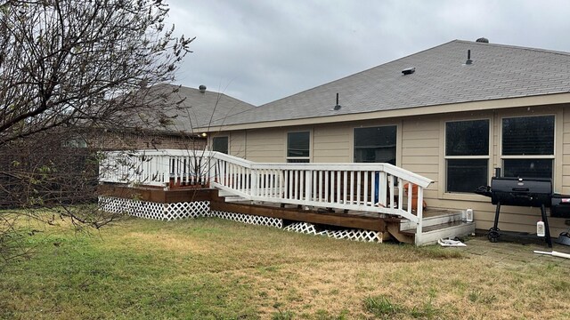 rear view of house featuring a deck and a lawn