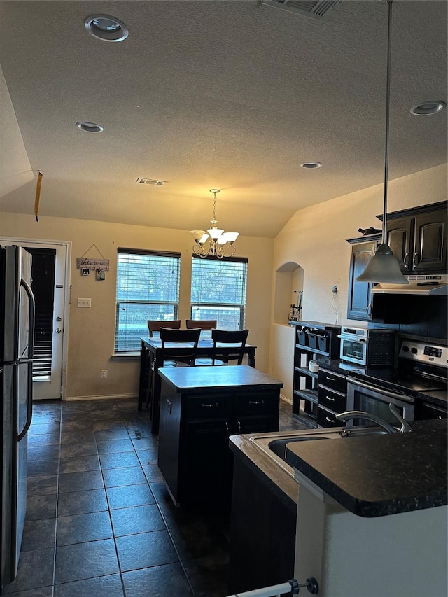 kitchen featuring stainless steel appliances, a kitchen island with sink, decorative light fixtures, an inviting chandelier, and lofted ceiling