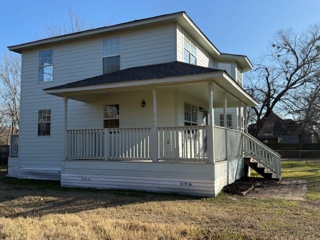 back of property featuring covered porch and a lawn